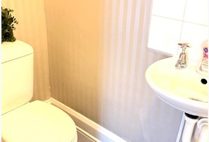 A bathroom with a toilet, a sink, and a shower area. - Ground Floor Studio - Willesden Green - Sleeps 4 (London)