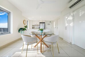 A modern kitchen with a central island, white cabinetry, and a large window. - Capital Panorama Central City Escape w Pool and Gym (Darwin)