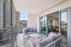 Un balcon avec un canapé, une table et une porte vitrée donnant sur le salon.