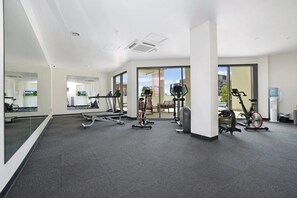 A modern gym with cardio machines, free weights, and a mirrored wall. - Capital Panorama Central City Escape w Pool and Gym (Darwin)