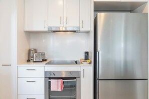 A modern kitchen with stainless steel appliances, including a refrigerator, oven, and toaster. - Capital Panorama Central City Escape w Pool and Gym (Darwin)