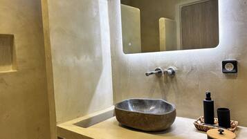 A bathroom with a stone sink, a mirror, and a towel rack.