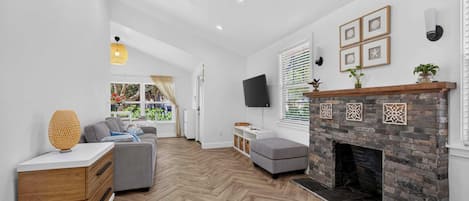 A modern living room with a fireplace, a sofa, a coffee table, and a television.