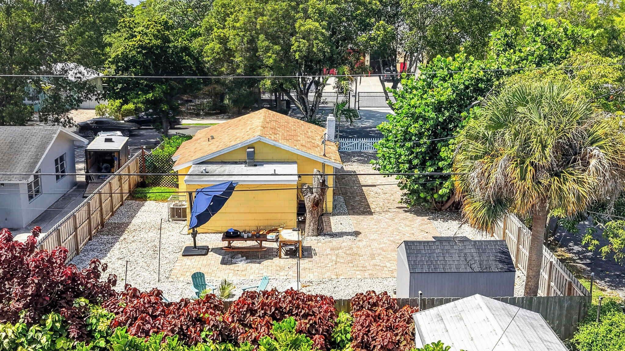 A residential property with a yellow house, a covered patio, and a fenced yard.
