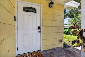 A white door with a small window above it, a doorbell, and a mailbox on the right side. - The Banana Cabana - Cozy Cottage (West Palm Beach)