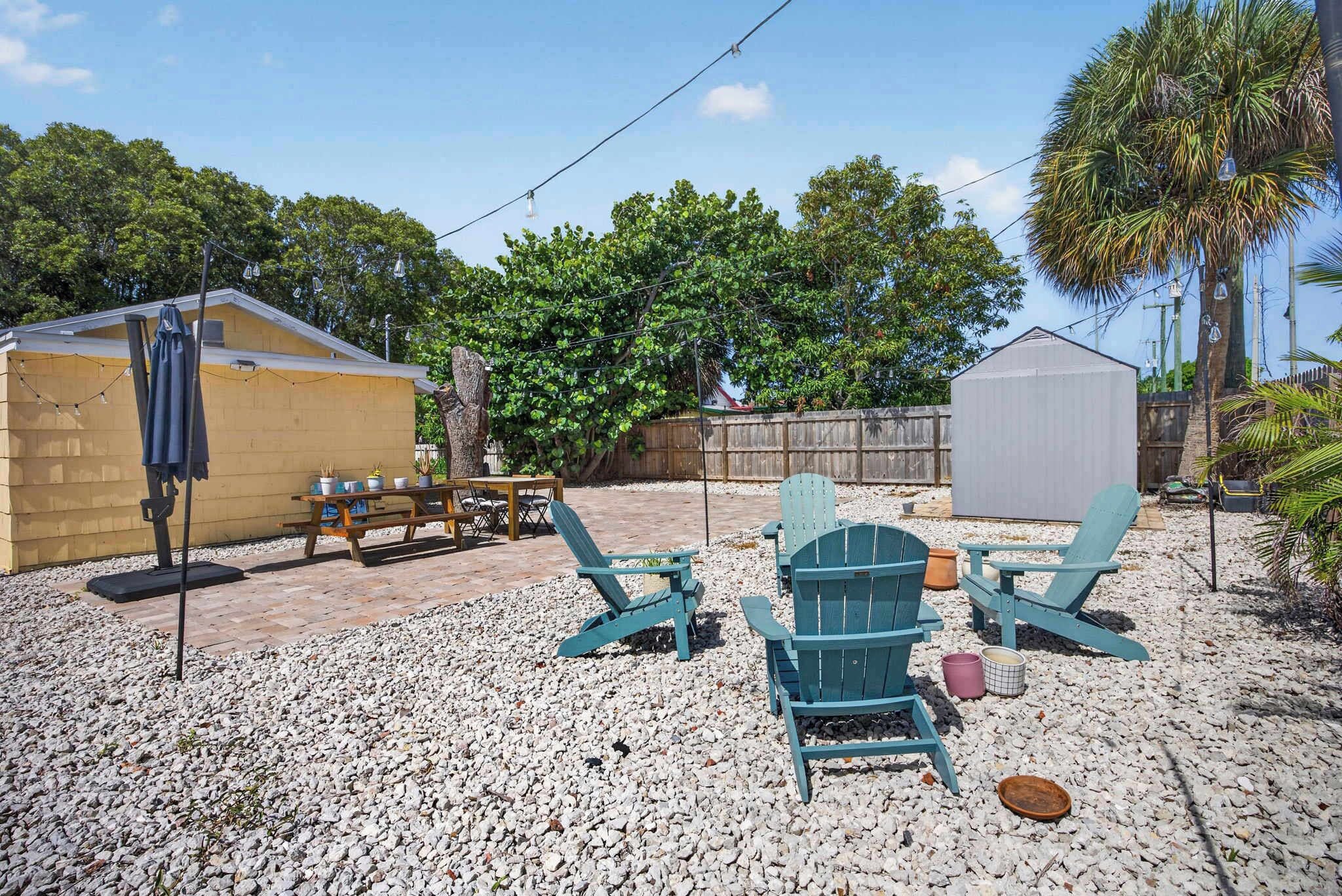 A backyard with a patio area, outdoor furniture, and a covered structure.