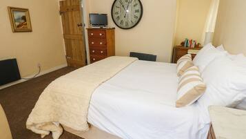 Un dormitorio con cama, reloj, televisor y armario.