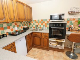 A kitchen with wooden cabinets, a microwave, an oven, a sink, and a tiled backsplash.