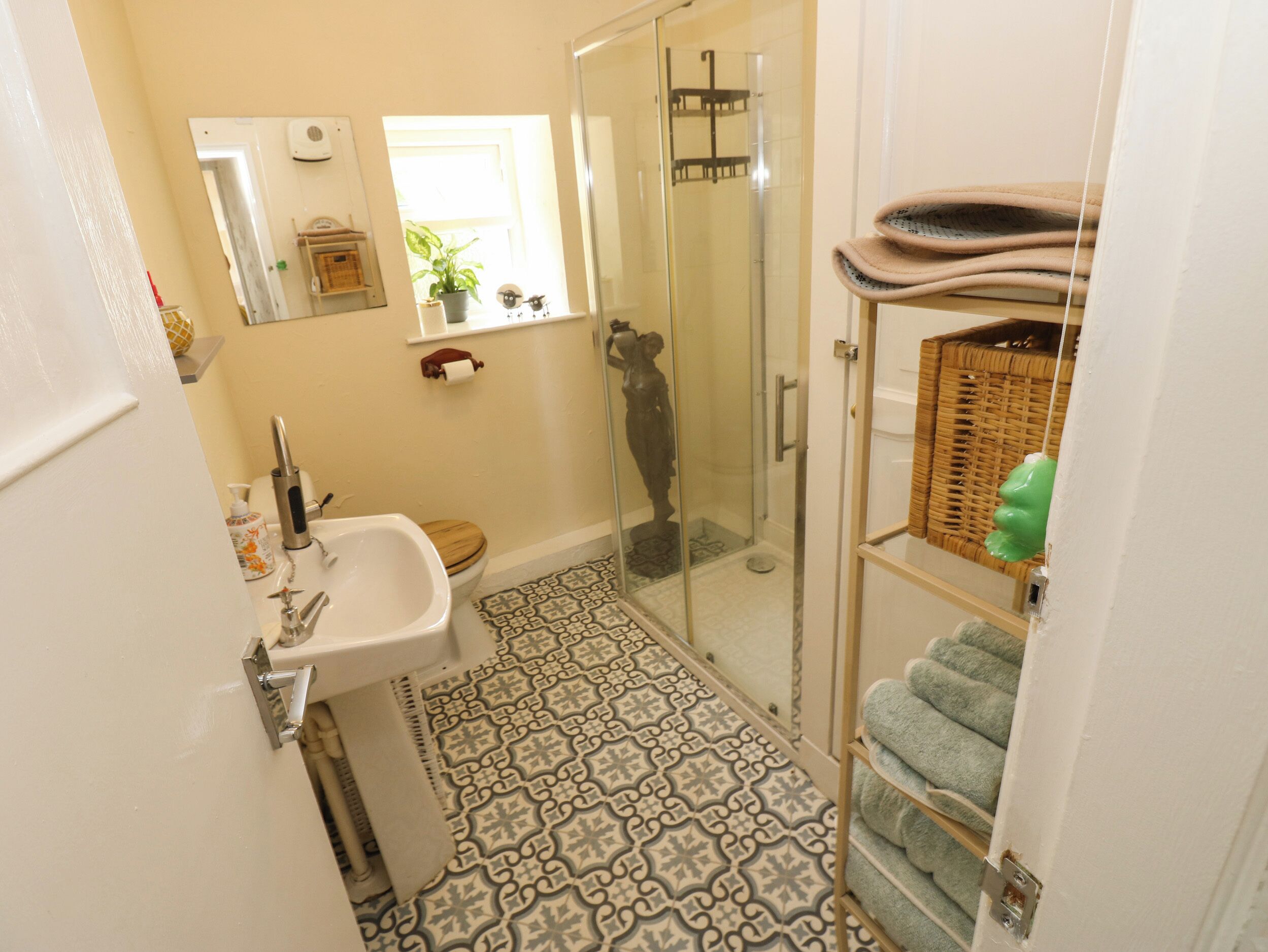 Un baño con ducha, lavamanos y baldosas de suelo estampadas.
