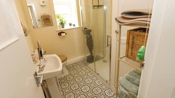 Un baño con ducha, lavamanos y baldosas de suelo estampadas.