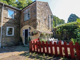 A stone building with a red picket fence, a door, and a window.