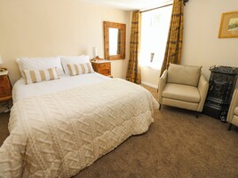 A bedroom with a large bed, a chair, a dresser, and a mirror on the wall.