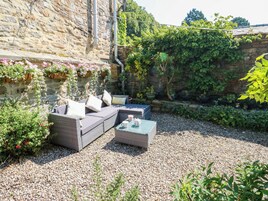 A patio with wicker furniture, a table, and a stone wall.