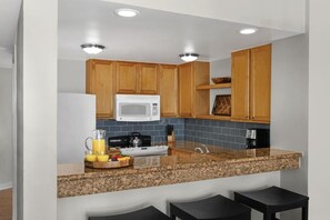 A modern kitchen with wooden cabinets, a microwave, granite countertop, and a coffee maker. - Ocean View - Marriott's Monarch Sea Pines (Hilton Head Island)