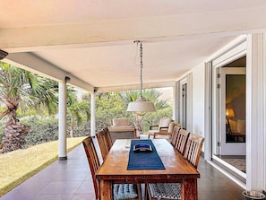 An outdoor covered patio with a dining table, chairs, and a hanging light fixture. - Villa Sunrise Indigo – Spacious Retreat with Gorgeous Sea Views (Cul-de-Sac)