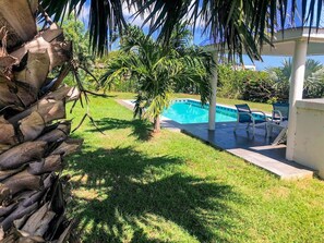 Ein Garten mit Swimmingpool, Palmen und einer Terrassenanlage mit Sitzgelegenheiten.