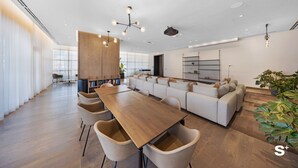 A modern interior with a wooden dining table, beige chairs, a sofa, and a large window. - Cozy Miami Studio - Pool & Gym - Views (Miami)