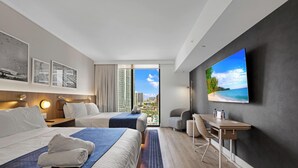 A hotel room with a bed, a desk, a chair, a TV, and a view of the city. - Cozy Miami Studio - Pool & Gym - Views (Miami)