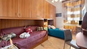 Een kamer met een houten garderobe, een bank, een bed, een bureau en een stoel.