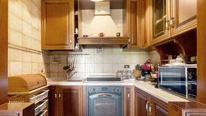Een keuken met houten kastjes, een fornuis en een magnetron.