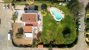 Vista aérea de una propiedad residencial con piscina, garaje independiente y una casa grande con tejado de tejas.