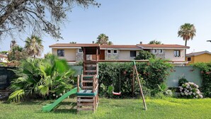Una propiedad residencial con un columpio de madera, un tobogán verde y un césped bien cuidado.
