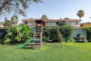 A residential property with a wooden swing set, a green slide, and a well-maintained lawn. - Villa Matilde Domo Boutique - Suite Pietra di Sale (Torre degli Ulivi)