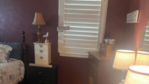 A bedroom with a bed, a chair, a desk, a dresser, a window with blinds, and a lamp. - Cute and cozy 3 bedroom 2 bath home. Close to TTU and LCU as well! (Lubbock)
