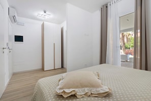 A bedroom with a bed, a wardrobe, a door with a handle, a light switch, and a window with curtains. - Villa Matilde Domo Boutique - Barby Room (Torre degli Ulivi)
