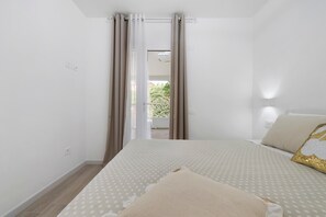 Ein Schlafzimmer mit Bett, Vorhängen, Blick nach draußen und einem Fenster.