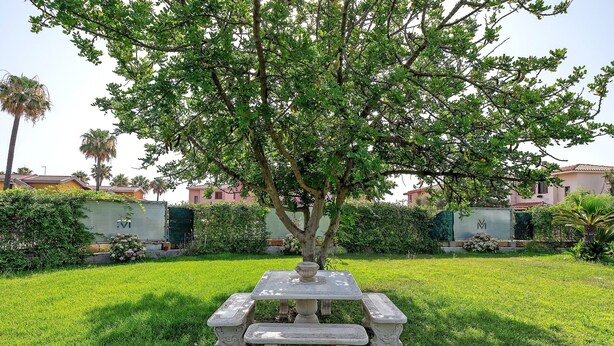 A garden with a stone table and bench, surrounded by well-maintained grass and trees. - Villa Matilde Domo Boutique - Barby Room (Torre degli Ulivi)