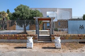 A building with a concrete facade, a metal gate, and a paved entrance with steps leading to a door. - Villa Matilde Domo Boutique - Barby Room (Torre degli Ulivi)