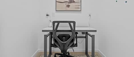 A modern office space with a desk, chair, and a framed picture on the wall.