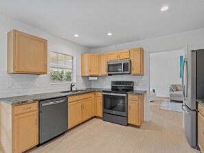 A modern kitchen with wooden cabinets, a black dishwasher, a stainless steel refrigerator, and a built-in oven. - Charming and secluded Jupiter hideaway close to everything!  Pet friendly (Jupiter)