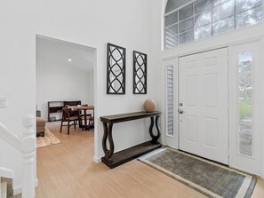 A clean, modern entryway with a wooden floor, a console table, and two wall-mounted decorative frames. - Charming and secluded Jupiter hideaway close to everything!  Pet friendly (Jupiter)