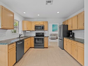A modern kitchen with wooden cabinets, stainless steel appliances, and a tiled backsplash. - Charming and secluded Jupiter hideaway close to everything!  Pet friendly (Jupiter)