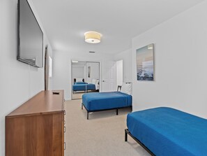 A hotel room with a wooden desk, two single beds, a large mirror, and a painting on the wall. - Charming and secluded Jupiter hideaway close to everything!  Pet friendly (Jupiter)