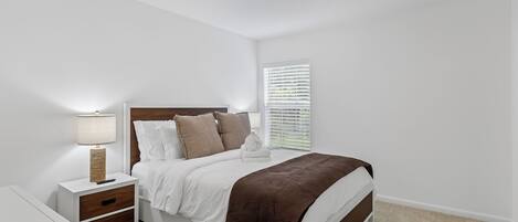 Un dormitorio con una cama, mesitas de noche, una lámpara y una lámpara de techo.