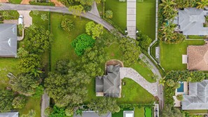 An aerial view of a residential area with a curved driveway, green lawns, and various trees. - Charming and secluded Jupiter hideaway close to everything!  Pet friendly (Jupiter)