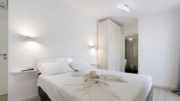 Ein modernes Schlafzimmer mit einem großen Bett, Nachttischen und Wandleuchten.