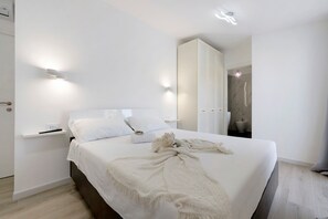 A modern bedroom with a large bed, bedside tables, and wall-mounted lighting. - Villa Matilde Domo Boutique – Suite Pietra Daniele (Torre degli Ulivi)