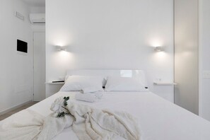 Een minimalistisch hotelkamer met een groot bed, twee nachtkastjes en wandlampen.