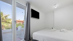 Ein Schlafzimmer mit einem Bett, einem Fernseher und einer Schiebetür zum Balkon.