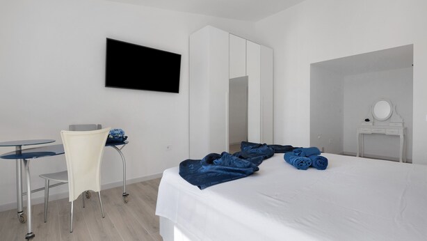 A hotel room with a bed, a desk, a chair, a TV, a wardrobe, and a bathroom. - Villa Matilde Domo Boutique - Master Suite with Sea View (Torre degli Ulivi)