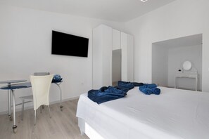 Ein Hotelzimmer mit Bett, Schreibtisch, Stuhl, Fernseher, Kleiderschrank und Bad.