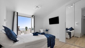 A modern bedroom with a bed, a TV, a mirror, and a balcony view. - Villa Matilde Domo Boutique - Master Suite with Sea View (Torre degli Ulivi)