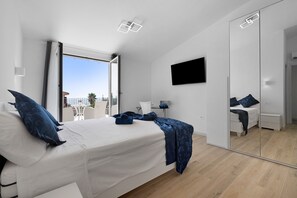 A modern bedroom with a bed, a TV, a mirror, and a balcony view. - Villa Matilde Domo Boutique - Master Suite with Sea View (Torre degli Ulivi)