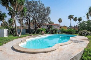 A swimming pool with a curved edge, surrounded by a grassy area and palm trees. - Villa Matilde Domo Boutique - Master Suite with Sea View (Torre degli Ulivi)
