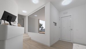 A modern room with a flat-screen TV, a door with a window, and a staircase leading to another area. - Villa Matilde Domo Boutique - Master Suite with Sea View (Torre degli Ulivi)