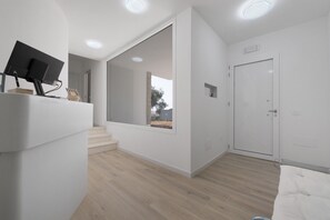 A modern interior with a staircase, a door with a small window, and a flat-screen TV mounted on the wall. - Villa Matilde Domo Boutique - Master Suite with Sea View (Torre degli Ulivi)